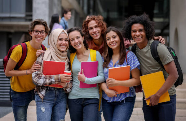 Multi-ethnic group of Latin American college students smiling at the university campus and looking at the camera - education concepts